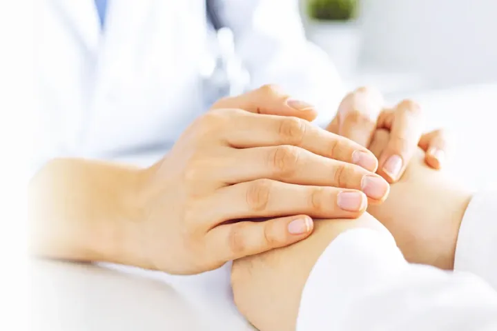患者の手を包む医師の手のイメージ