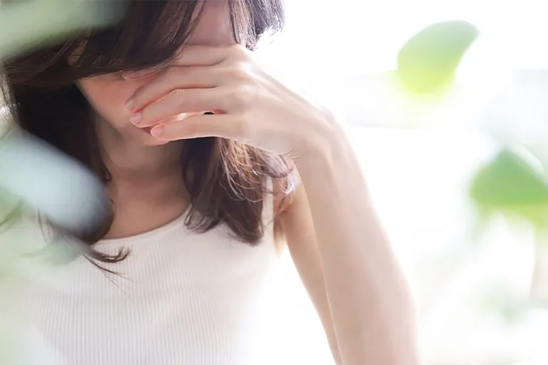 頭を押さえうつむきの女性